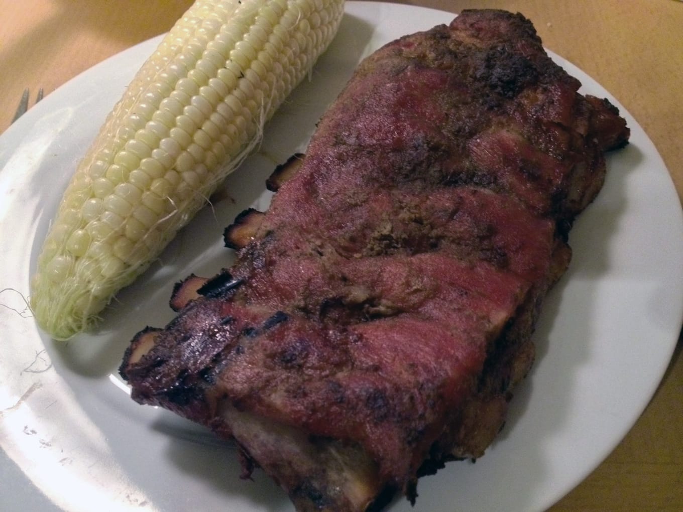 Spare ribs with a side of corn on the plate.